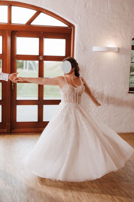 Suknia ślubna z gorsetową górą oraz kwiatowymi dekoracjami.