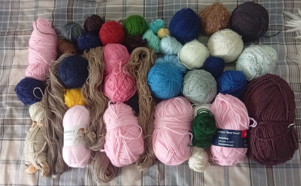 Novelos, medas e restos de lã de várias cores e tamanhos