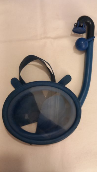 Máscara de mergulho azul com um tubo de respiração acoplado, comumente usada para snorkeling ou natação recreativa.