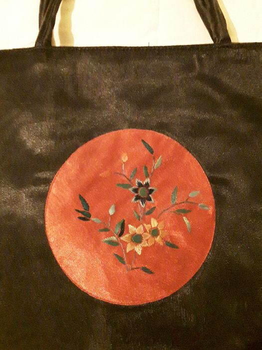 Bolsa ou mala de mão preta com aplicação circular vermelha