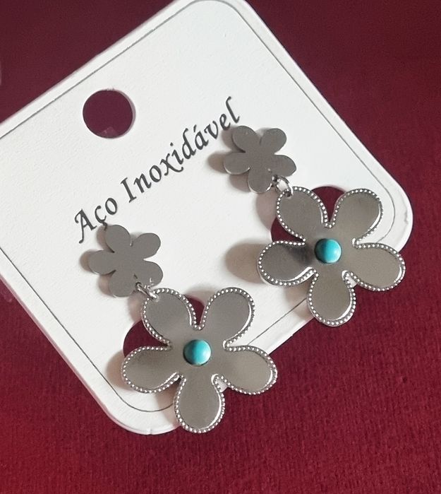 Brincos prateados, em aço, 2 flores de diferentes tamanhos com 1 pedrinha turquesa.