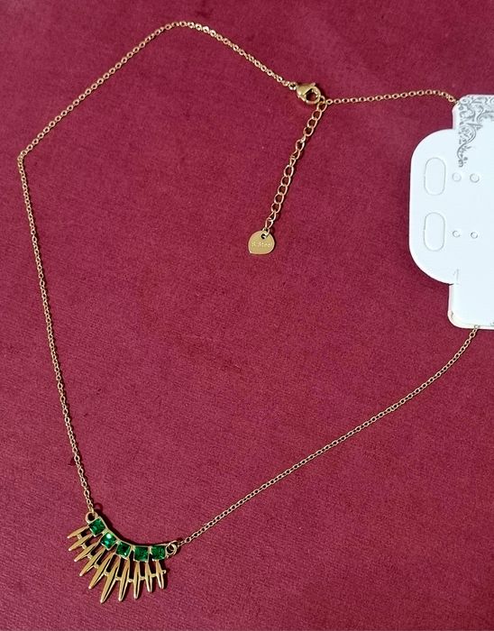 Colar dourado, em aço, com 5 pedrinhas quadradas verdes. Tem extensor.