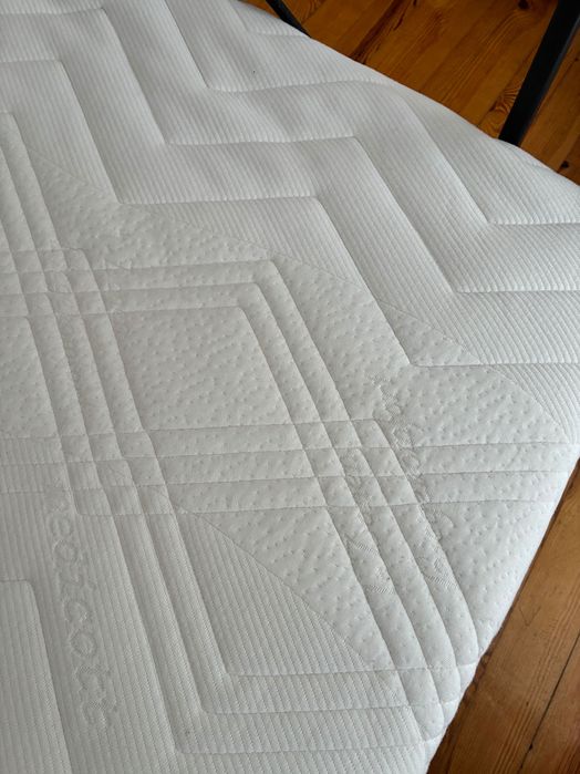 Łóżko z metalową ramą i materacem.