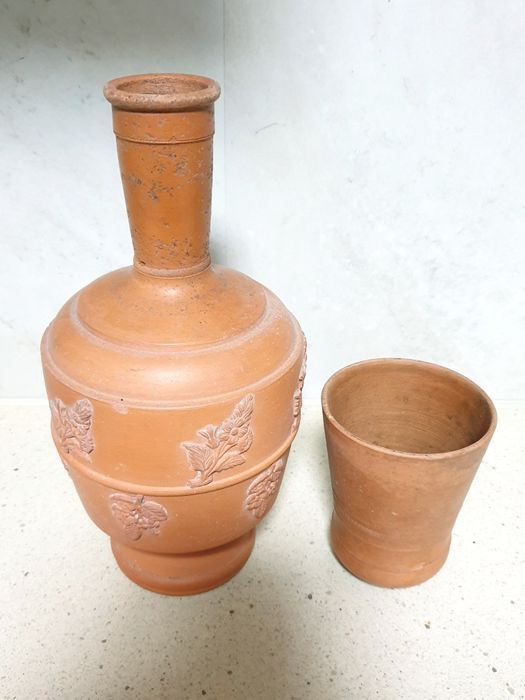 Antiga garrafa de água com copo em barro