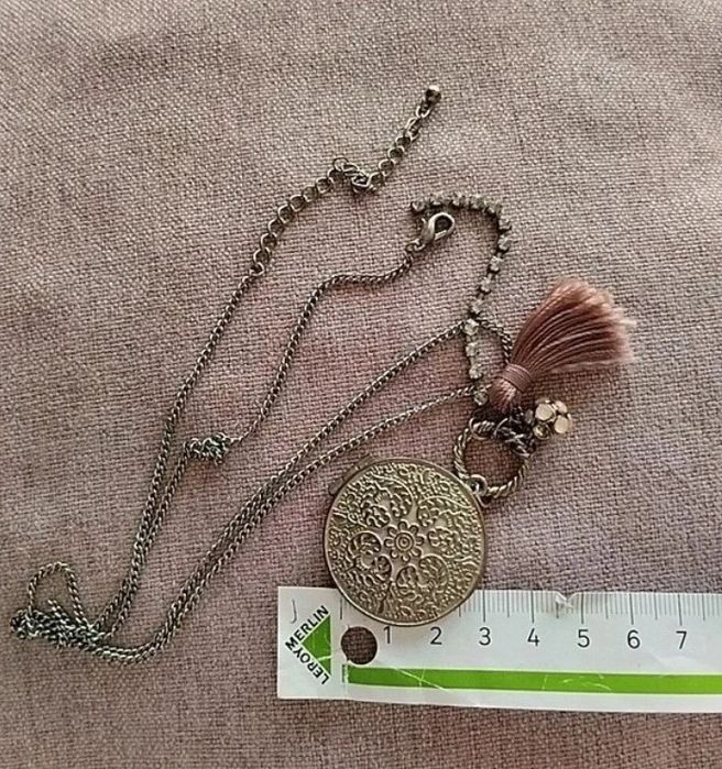 Colar com medalhão floral e borla rosa.
