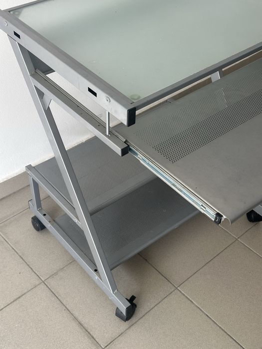Secretária de computador compacta em metal e vidro.