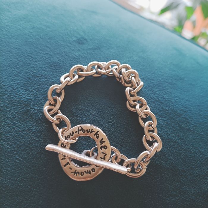 Pulseira em aço prateado com fecho com inscrição.