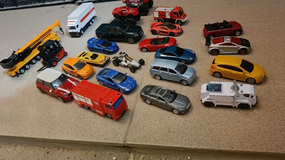 zestaw kolekcjonerskich modeli samochodów, takich jak resoraki marek Hot Wheels, Matchbox oraz modele Siku, w tym dźwig i ciężarówka Poczty Polskiej
