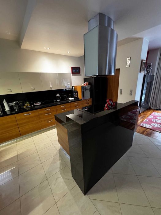 Kuchenna wyspa z zabudową meblową i granitowym murkiem.