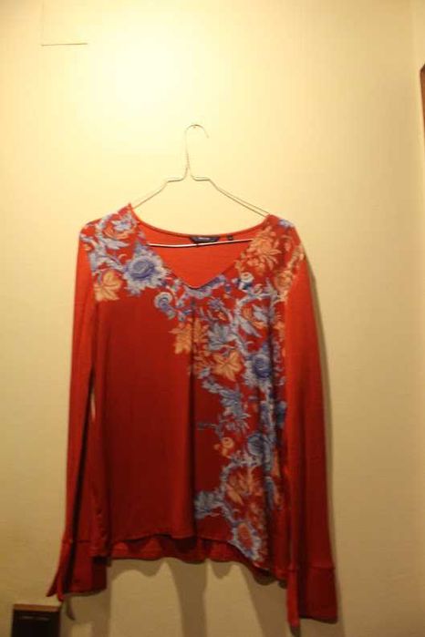 Blusa romântica com motivos florais azuis em fundo vermelho