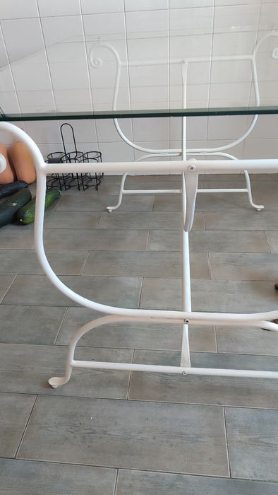 Mesa em ferro forjado com tampo de vidro.