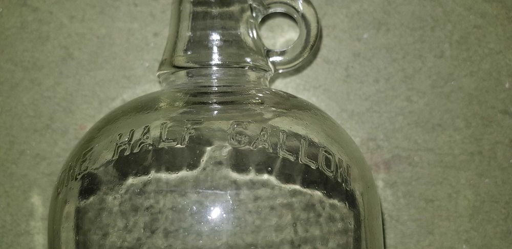 Garrafões de vidro com pega "ONE GALLON" e "ONE HALF GALLON"