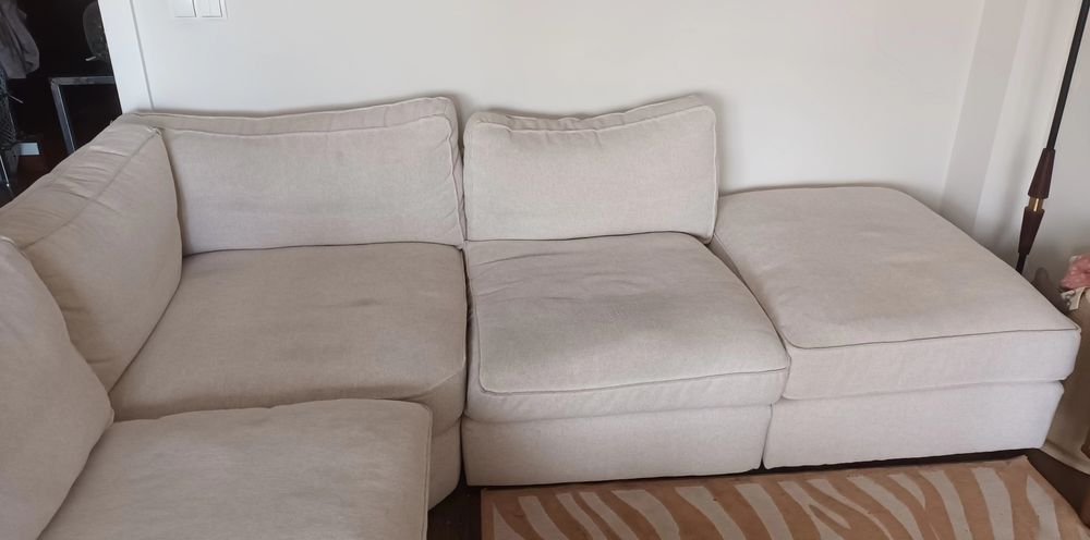 Sofá de canto bege, gato preto