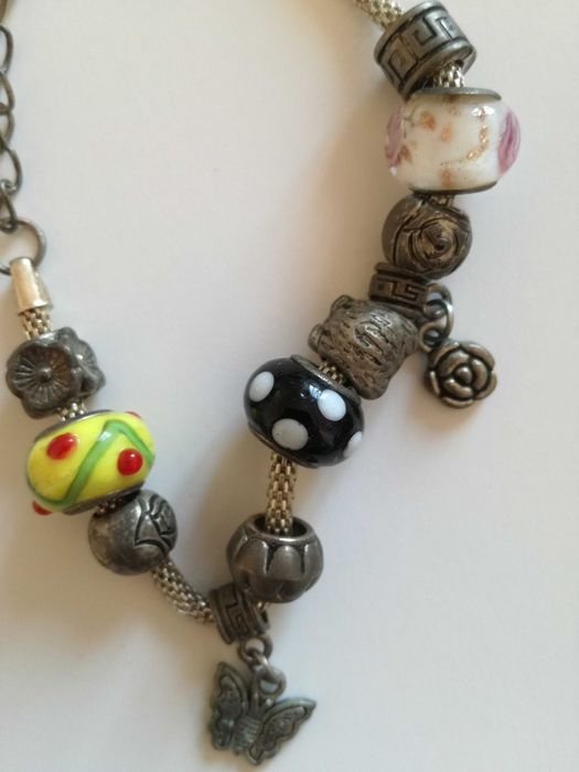 Pulseira com onze berloques variados, incluindo três bolas em vidro