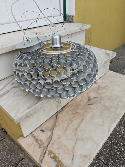 Lâmpada de teto feita de tubos de alumínio.
Luminá