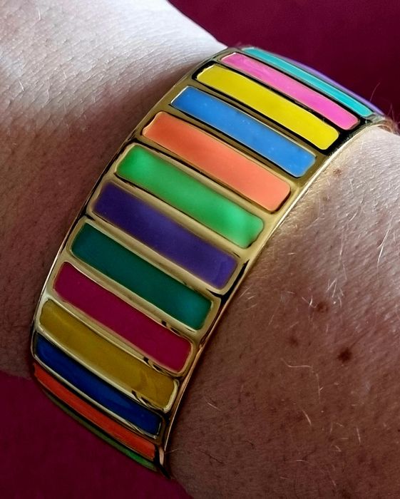 Pulseira dourada, em aço, com riscas coloridas. Fácil colocação.