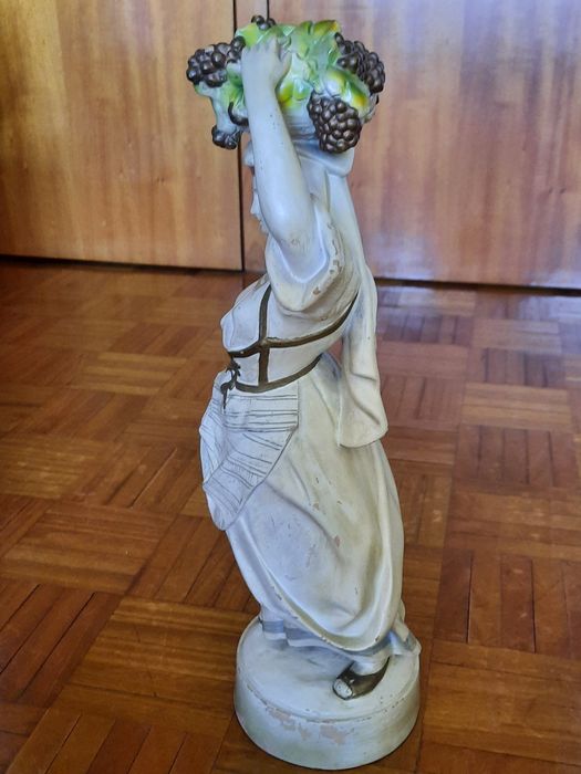 Estatueta decorativa em porcelana - camponesa com cesto de uvas