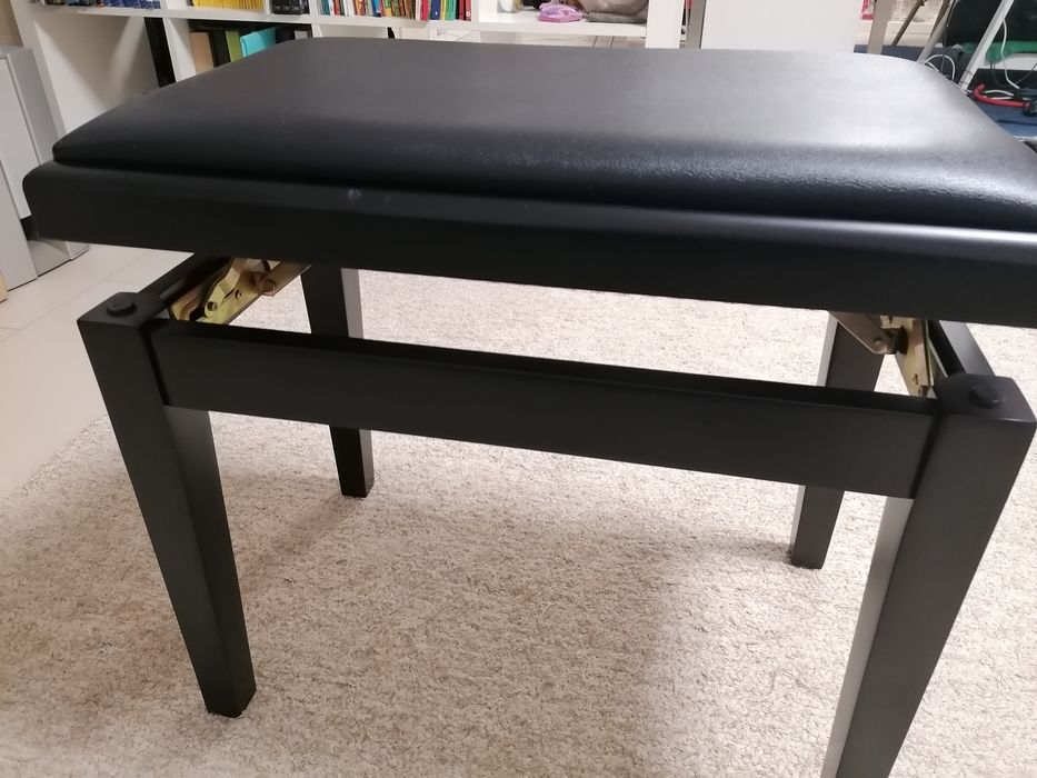 Banco de piano com assento e pele preta.