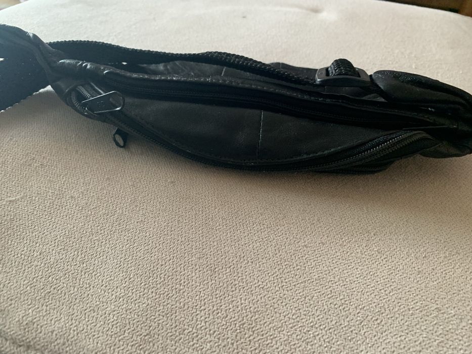 Bolsa de cabedal preta, é uma pochet classica de cintura com fecho.