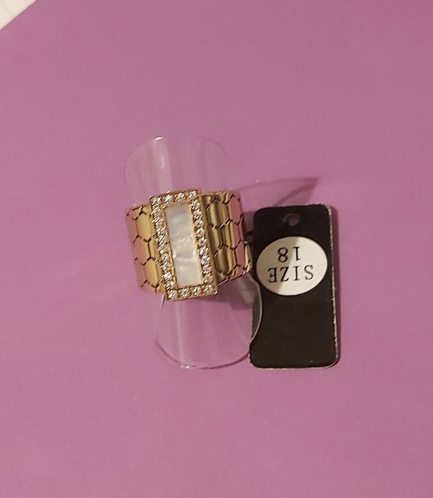 Anel dourado, em aço trabalhado, com uma madrepérola retangular rodeada de zirconias. T18