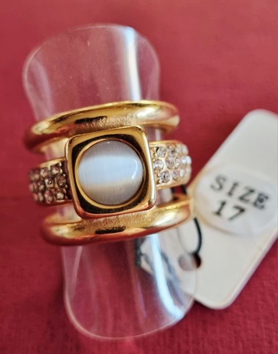 Anel dourado, em aço, com zirconias e uma pedra "olho de gato". T17