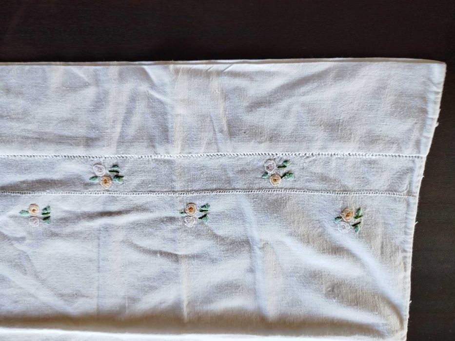 Lençol e almofada com flores bordadas a mão.