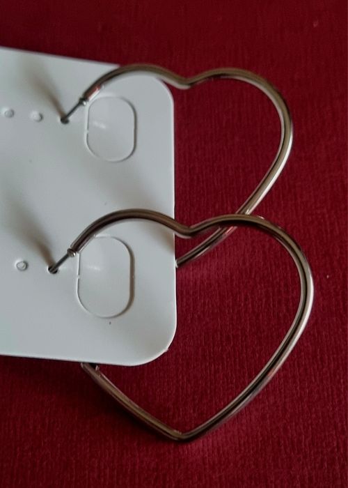 Brincos prateados, em aço, formato coração fininho.