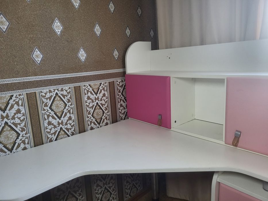 кутовий письмовий стіл для школяра з біло-рожевою надбудовою.