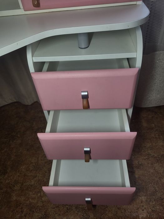 кутовий письмовий стіл для школяра з біло-рожевою надбудовою.