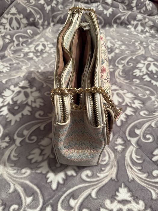 Mala a tiracolo branca com padrao colorido.