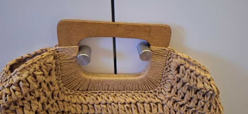 Bolsa de palha trançada com alça de mão.