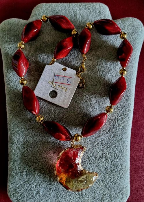 Colar dourado, em aço, com peças bordeaux em acrílico e uma meia lua.