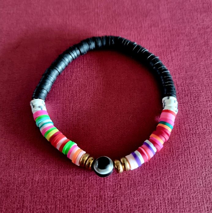 Pulseira elástica em tons de preto e multicor. Com olho de proteção