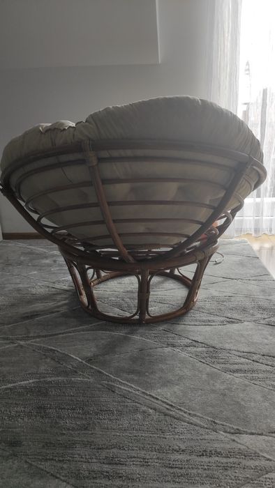 Duży fotel wiklinowy z poduszką.
