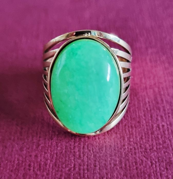 Anel dourado, em aço, com pedra oval verde claro. 18/ajustável