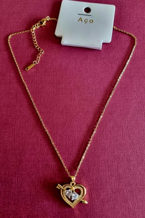 Colar dourado, em aço, com 2 corações unidos por uma flecha.