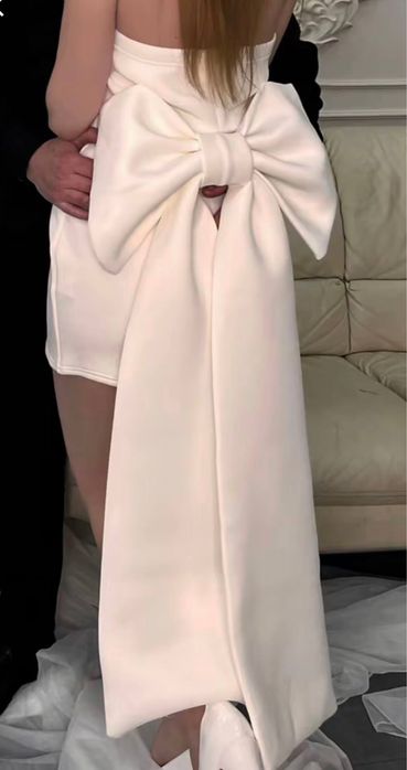 Біла сукня з великим бантом.