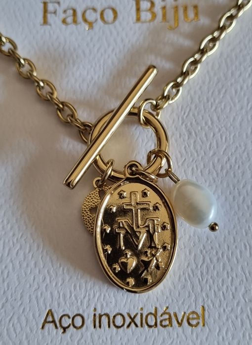 Colar dourado, em aço, com 3 pingentes diferentes. Fecho em T à frente