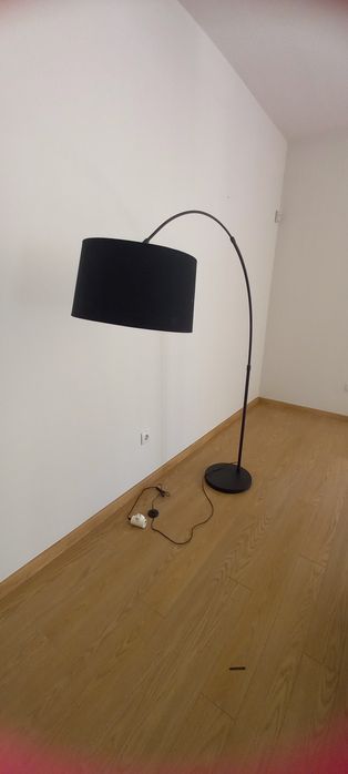 Candeeiro alto curvo, com base em metal preto.