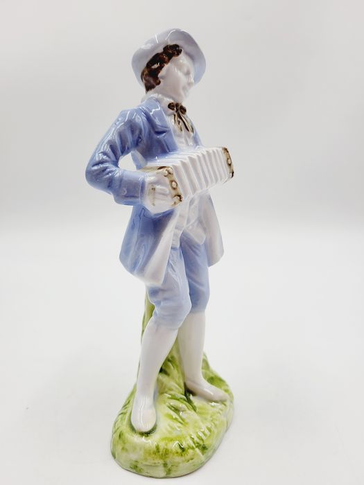 Ceramiczna pastelowa figurka muzykanta grajka z harmonią