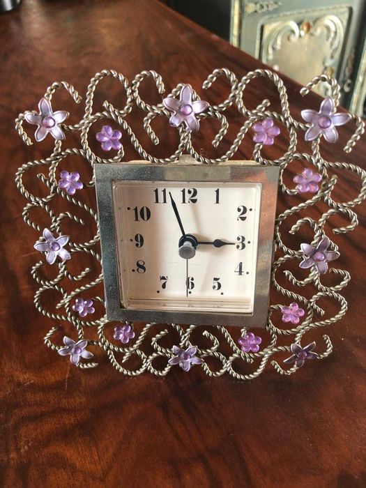 Relógio delicado em moldura trabalhada com flores em metal