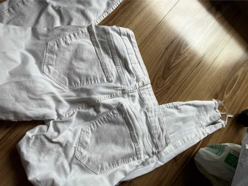 Spodnie białe z przetarciami dziurami szarpane zameczki na nogawce