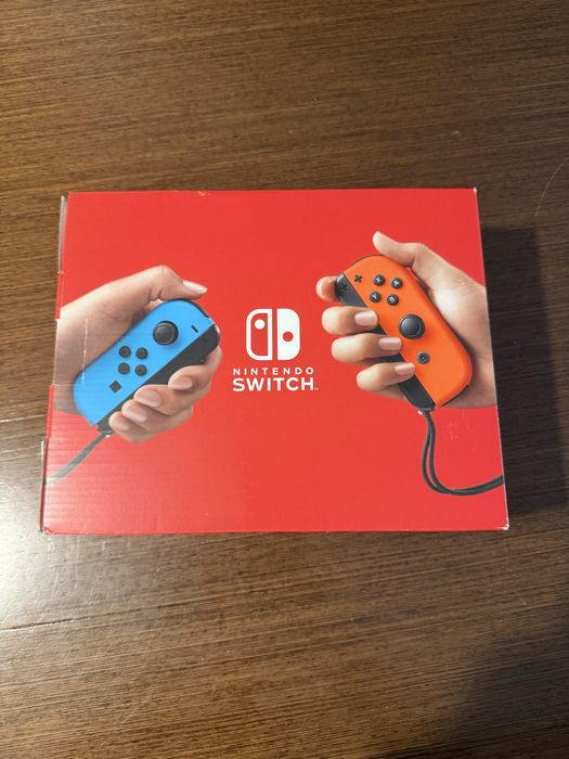 Vendo Nintendo Switch clássica com comandos Joy-Con azul e vermelho, em estado novo.