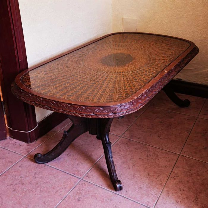 Mesa de centro antiga em madeira maciça com tampo em palhinha natural protegida por vidro.