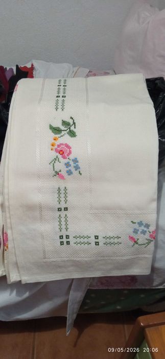 Um conjunto de lençóis e um conjunto de toalhas de mesa, ambos bordados.