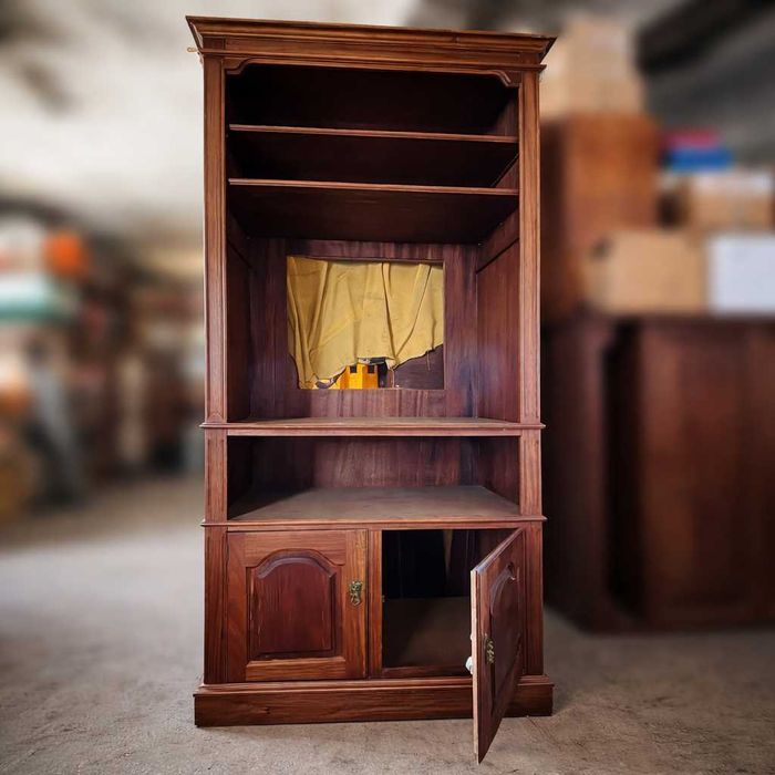 Estante em madeira maciça com prateleiras superiores e armário inferior com portas.