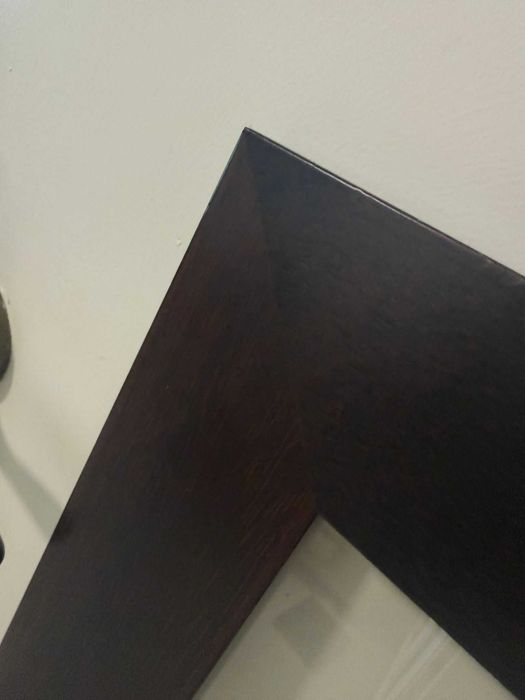 Quadro decorativo, com figuras geométricas em tons de vermelho e moldura de madeira castanha escura.