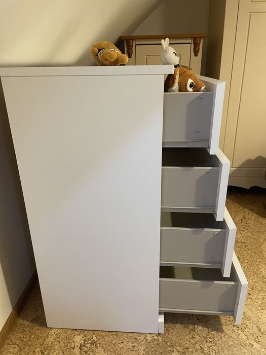 Biała komoda z głębokimi szufladami.
