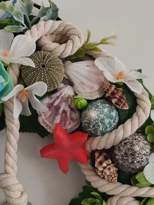 Guirlanda artesanal marítima com flores, conchas e farol decorativo
