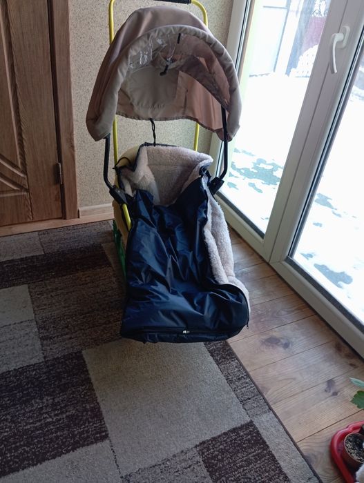 Дитячі санчата на колесах з капішоном.